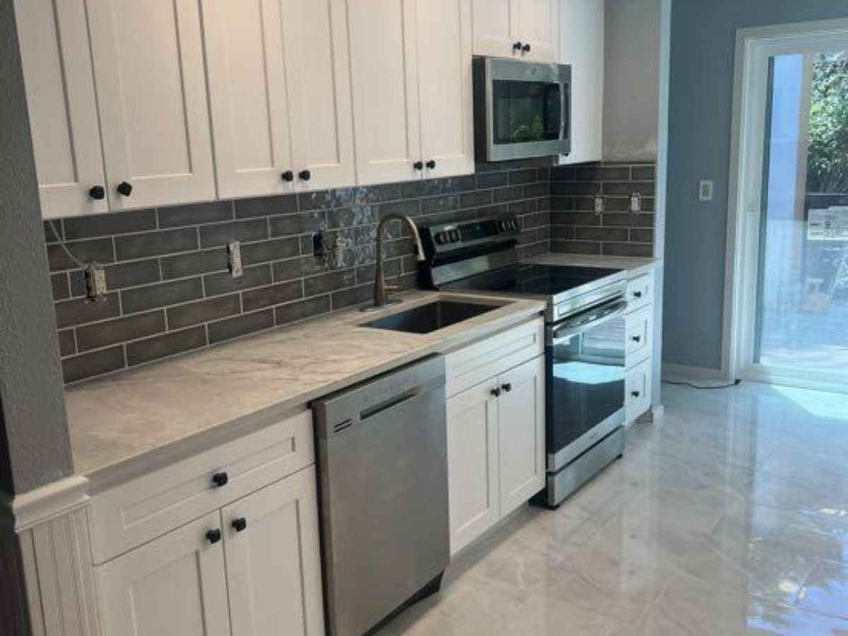 Kitchen remodel with white shaker cabinets, gray subway tile backsplash, stainless appliances and large-format tile floor